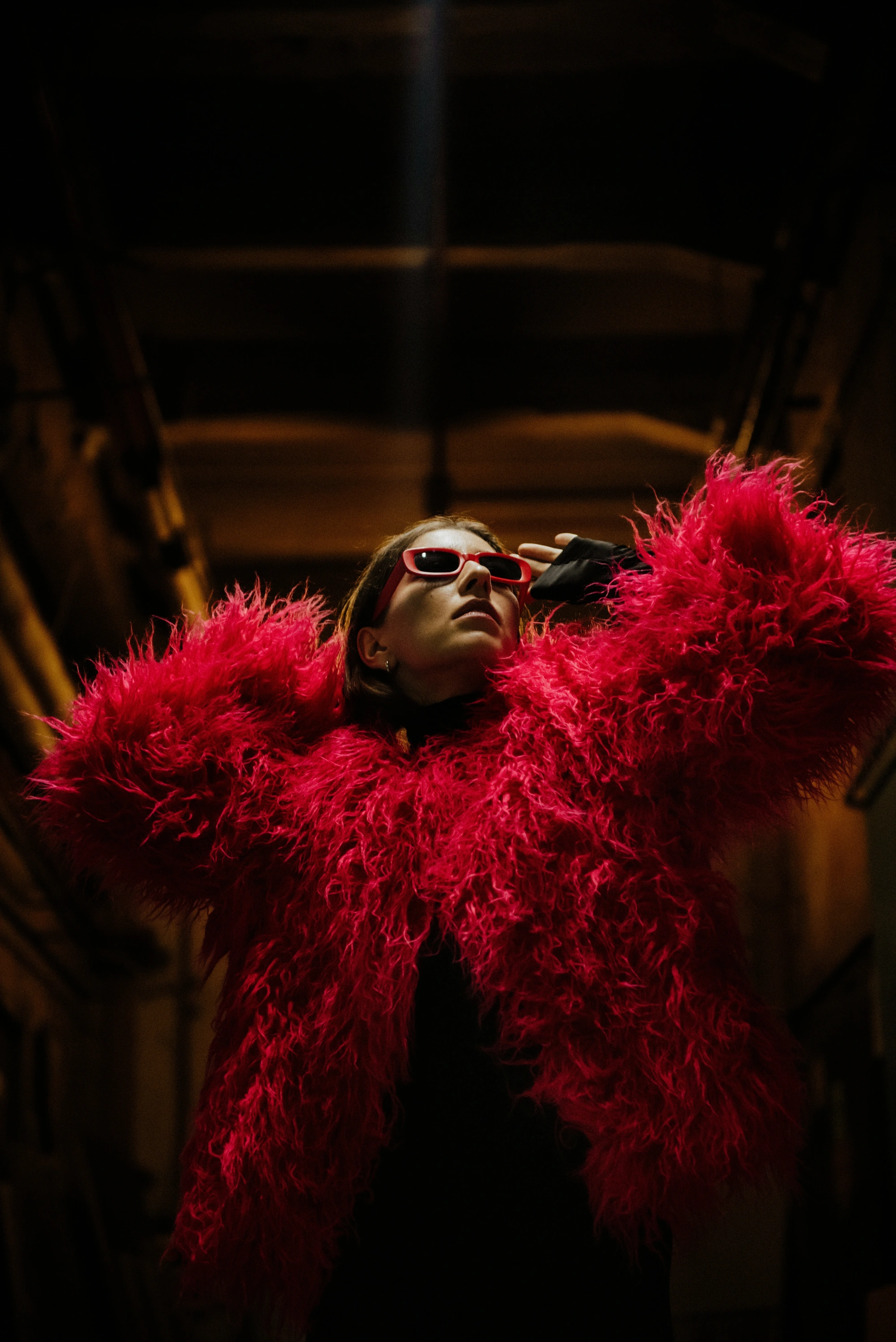 Red feathered fashion editorial photographed from below in warm directional light.