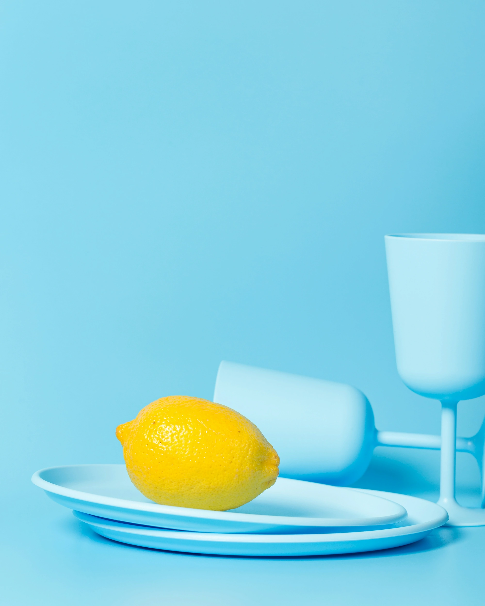 A bright lemon and cyan tableware in an editorial still-life photograph.